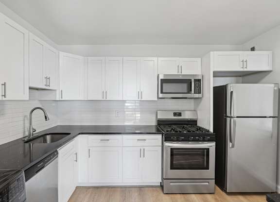 A kitchen with white cabinets and black countertops. at Stratford at Southern Towers, Alexandria