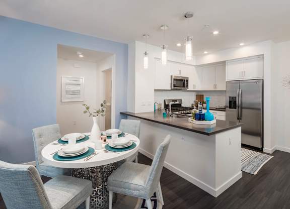 A modern kitchen with a dining table set for two.