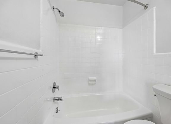 A white bathroom with a tub and toilet.