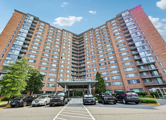 A large red brick hotel with a parking lot in front.