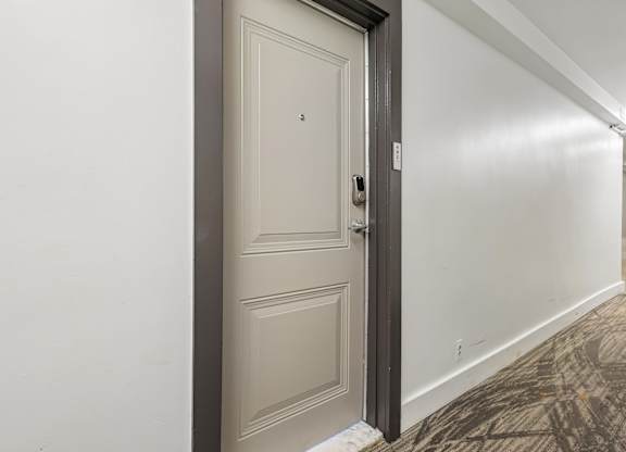 A white door with a black handle and a small square on the wall.