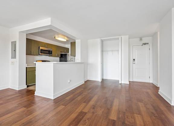 A kitchen with white walls and wooden floors.