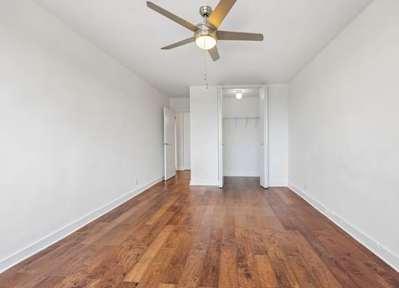 A room with a ceiling fan and wooden flooring.