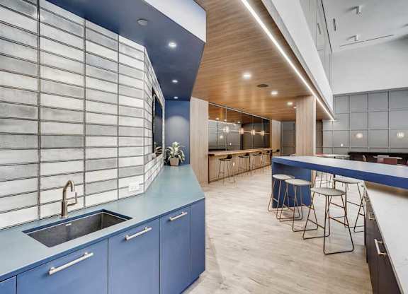 A modern kitchen with blue cabinets and a wooden ceiling.