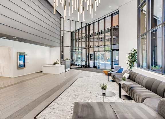 A modern art gallery with a long grey couch and a painting on the wall.