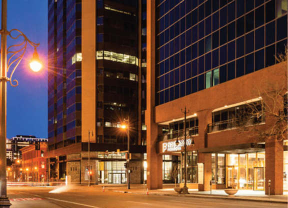 A tall building with a lit up sign that says "Parking" is next to a shorter building.