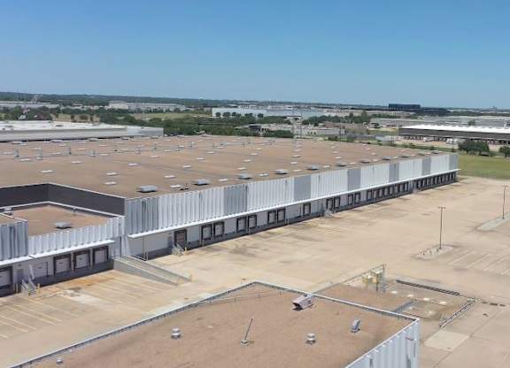 A large, empty parking lot with a clear blue sky above.