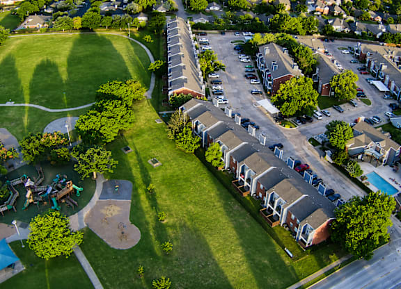An aerial view of a residential area with houses, a park, and a playground.