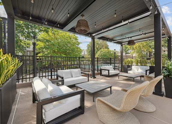 A patio with white cushioned furniture and a black metal fence.