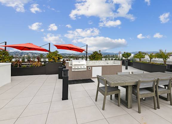 A patio with a table and chairs under red umbrellas.