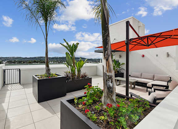 A balcony with a white couch and a red awning.