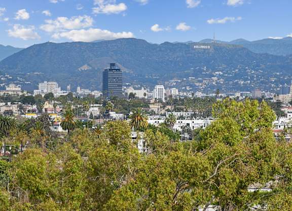 A cityscape with a mountain in the background and a sign that says Hollywood.