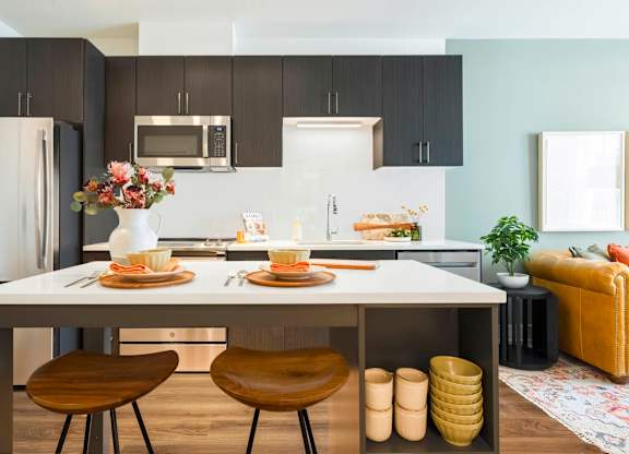 A modern kitchen with a dining table set for two.at The Vale at the Parks, Washington, DC 20012  