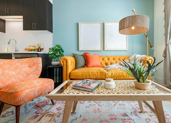 A living room with a yellow sofa, a patterned rug, and a wooden coffee table.at The Vale at the Parks, Washington, DC  
