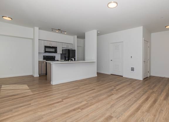 A kitchen with a white countertop and wooden flooring.