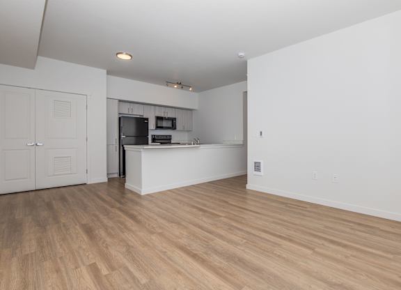 A kitchen with a white counter and wooden floors.