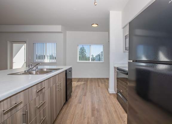 A modern kitchen with wooden floors and a black refrigerator.