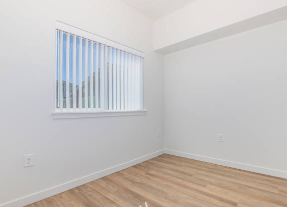 A room with a window and wooden flooring.