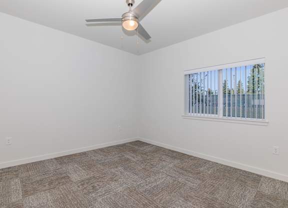 A room with a ceiling fan and a window with blinds.