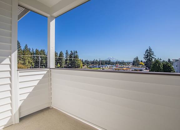 A balcony with a view of a parking lot and trees.
