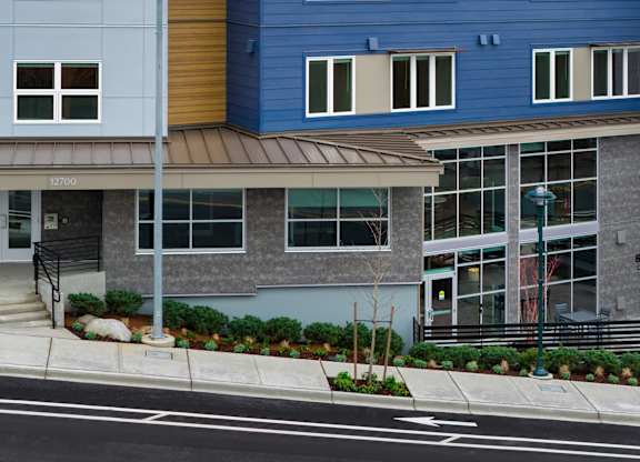 A blue building with a brown awning and a tree in front of it.