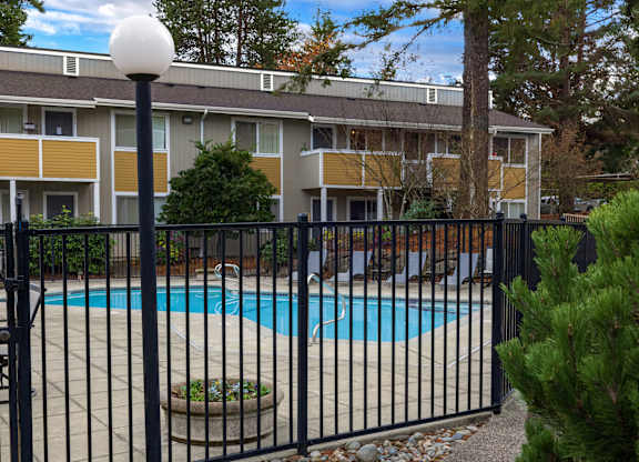 A pool surrounded by a black fence in front of a building.