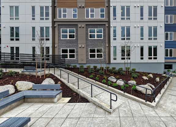A modern courtyard with a bench and a planter box.