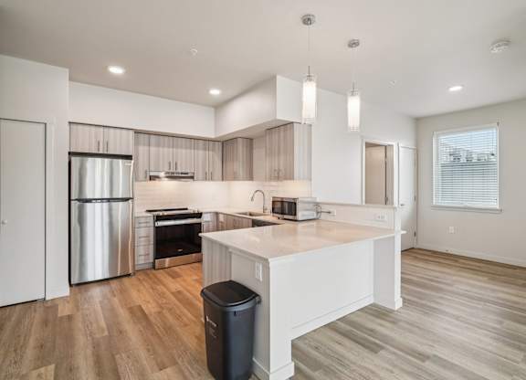 A modern kitchen with wooden floors and stainless steel appliances.