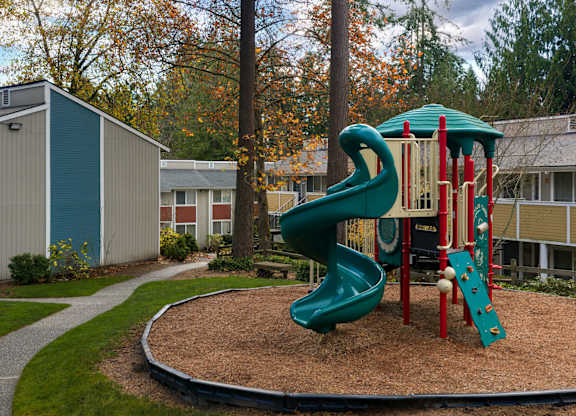 A playground with a green slide and red and white toy.