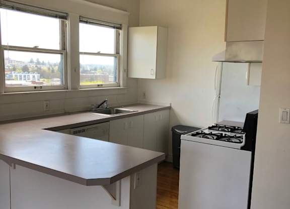 A kitchen with white cabinets and a white stove.