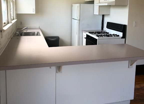 A kitchen with white cabinets and a stove top oven.