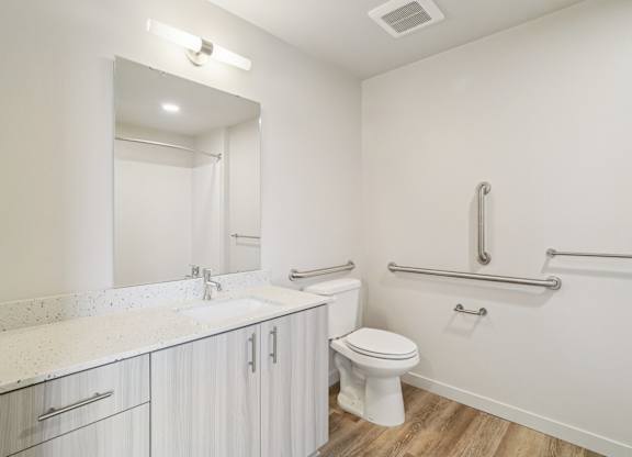 A white bathroom with a toilet, sink, and mirror.