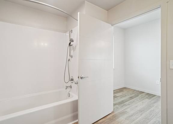 A white bathroom with a tub and a door.