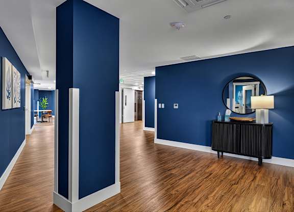 A long hallway with a blue wall and a mirror on the wall.