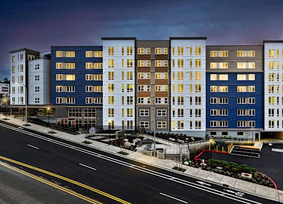 A modern apartment building with a parking lot in front.