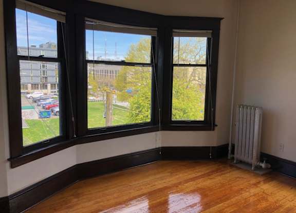 A room with wooden floors and a large window overlooking a parking lot.