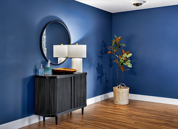 A room with a blue wall and a round mirror.