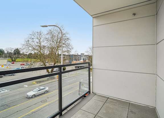 A car is parked on the street below a balcony.