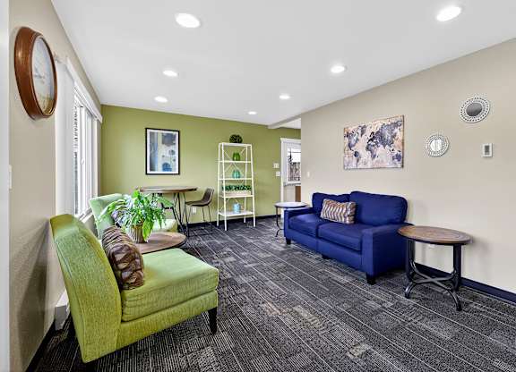 A living room with a green chair and a blue couch.