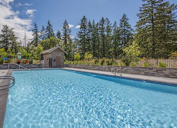 A small building is behind a pool.