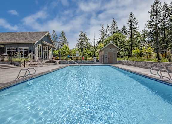 A large blue swimming pool with a small building in the background.