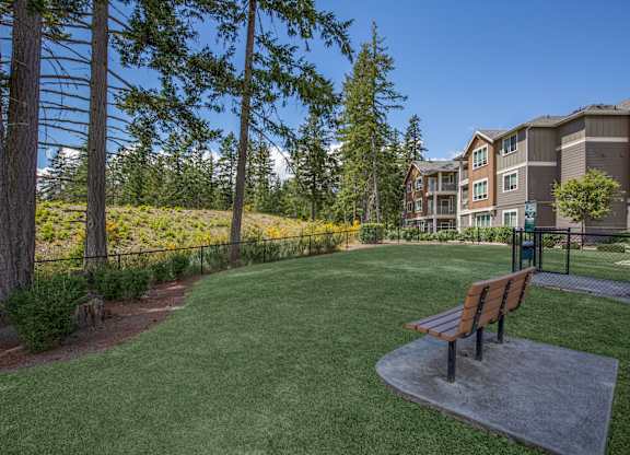 A park with a bench and a building in the background.