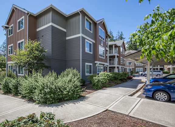 A modern apartment building with a parking lot in front.