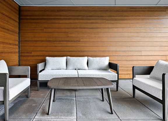 A modern living room with a wooden wall and a grey sofa.