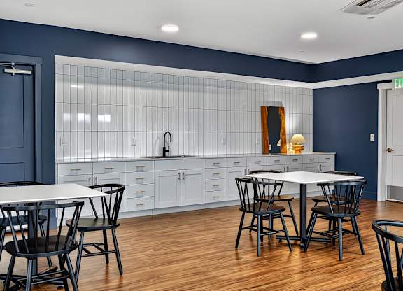 A kitchen with a table and chairs in front of a blue wall.