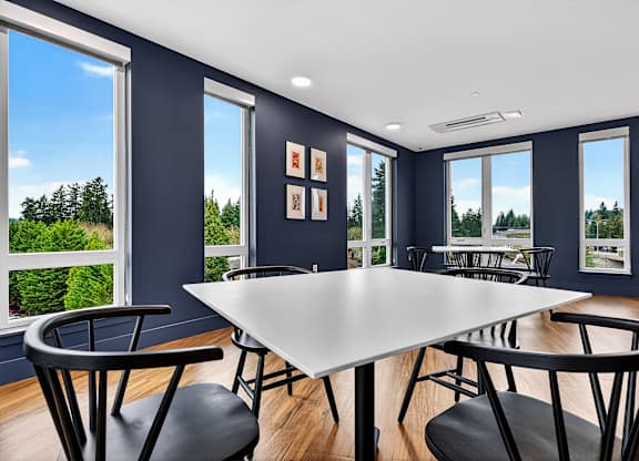 A dining room with a white table and black chairs.