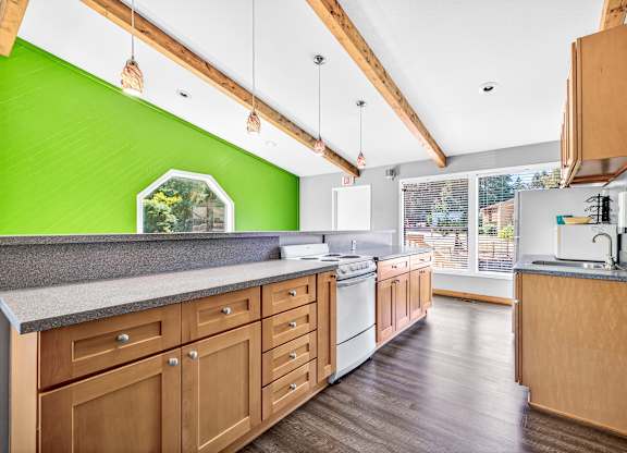 A kitchen with wooden cabinets and a green wall.