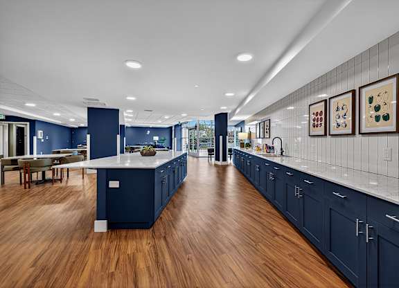 A modern kitchen with dark blue cabinets and a long white island.