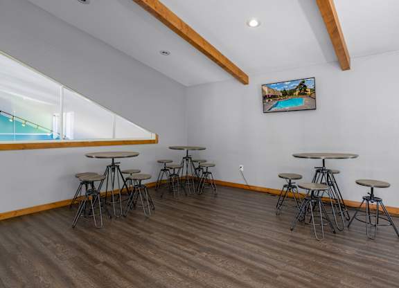A room with a long table and chairs and a picture of a pool on the wall.