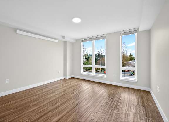 A room with wooden flooring and a window showing a view of trees.